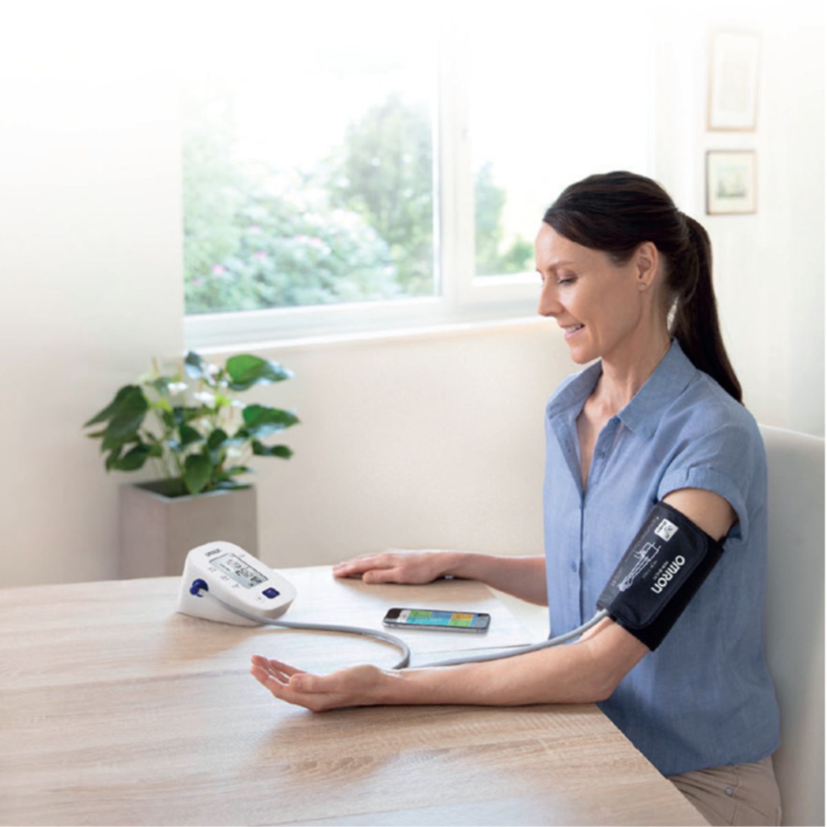 Mujer midiendo su presión usando tensiómetro OMRON HEM-7142 en casa